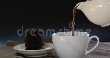 将热巧克力倒入<strong>棕色桌布</strong>上的<strong>白色</strong>陶瓷杯和模糊的dakr巧克力蛋糕上。 为每个人提供美味的饮料